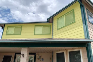 A two-story house with yellow siding and green trim