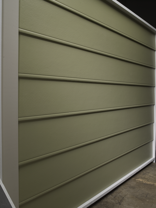 A siding sample in a warehouse of beaded seam siding that is army green.