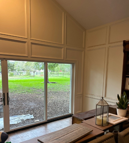 The inside of a home with a large sliding patio door and special moulding on the walls. 