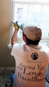 A construction worker applies caulk to a window frame.