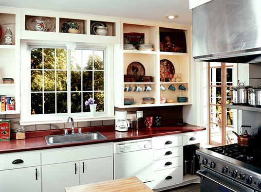 A bright kitchen image is displayed, featuring white cabinets, a red countertop, and a window.