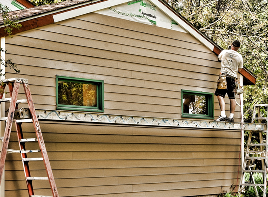 A man installs siding on a house