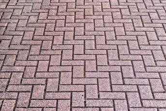 A brick outdoor flooring that is made of red brick and laid in a zig zag pattern. 