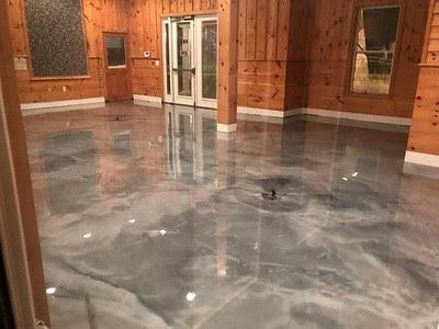 A room with wood walls with a grey epoxy coating that looks like marble.