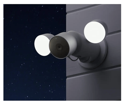 A Nest camera and flood light set with the lights on and a night sky in the background.