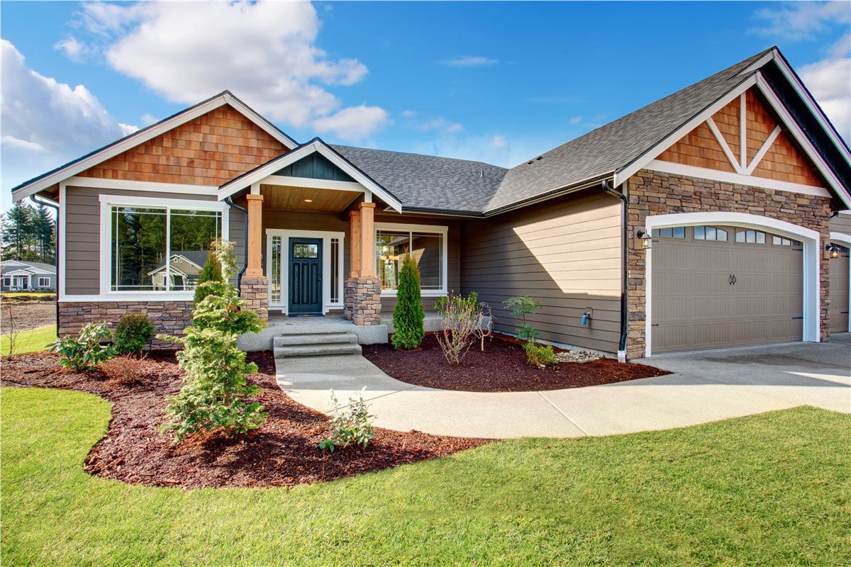 An exterior photo of a residential home with mixed siding, natural stone, and a covered porch.