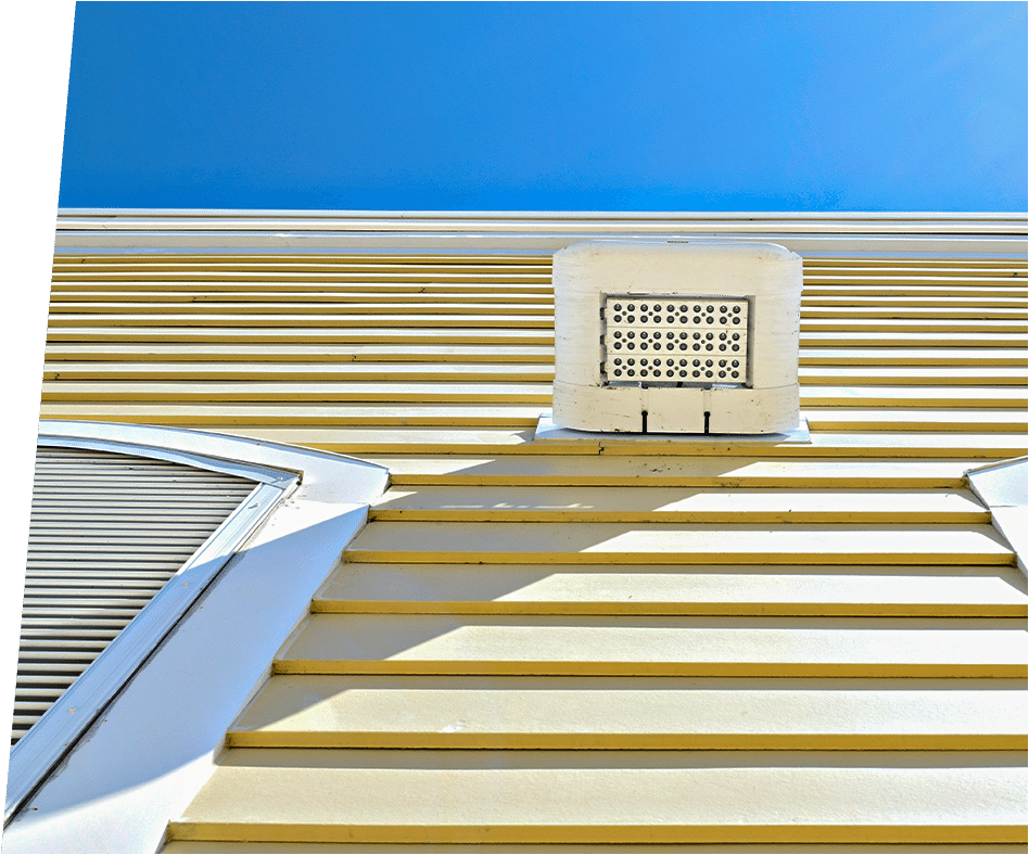 Close-up of yellow HardiePlank siding, with a white air vent and window.